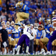 Dorian Thompson-Robinson of the UCLA Bruins jumps over Kamren Fabiculanan of the Washington Huskies in the second quarter at Rose Bowl Stadium on Sept. 30, 2022 in Pasadena, California.